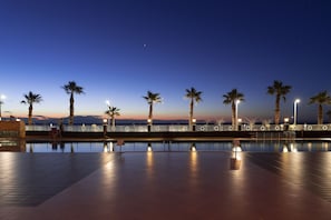 A nighttime pool area with palm trees and street lamps. - Crowne Plaza Hotel Antalya by IHG (Konyaalti)