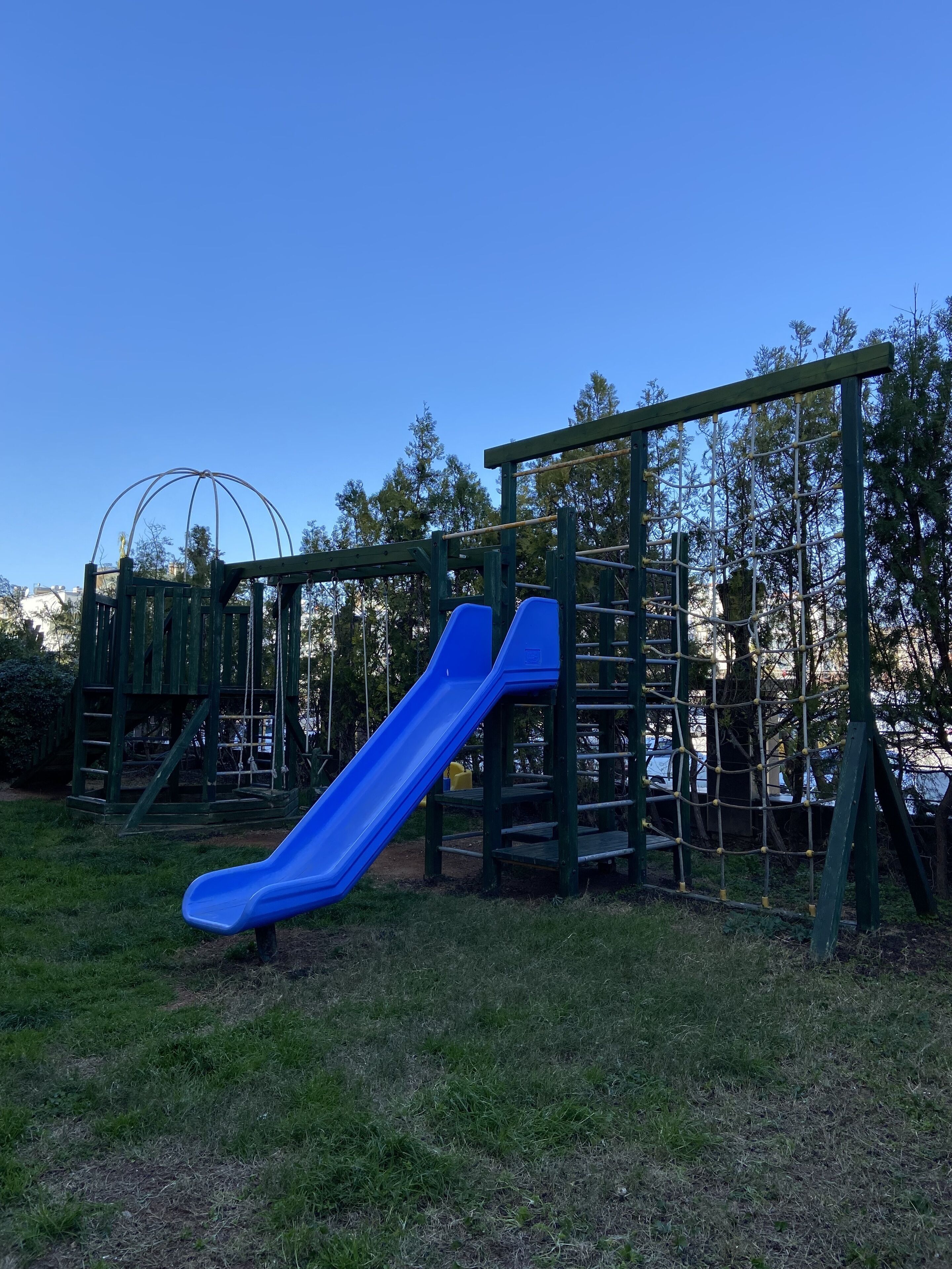 Un parque infantil con un tobogán azul y estructuras para escalar.