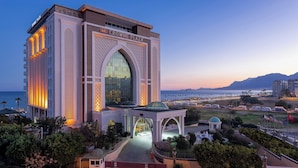 Um hotel com uma grande entrada em arco, uma área coberta com cúpula e vista para o mar.