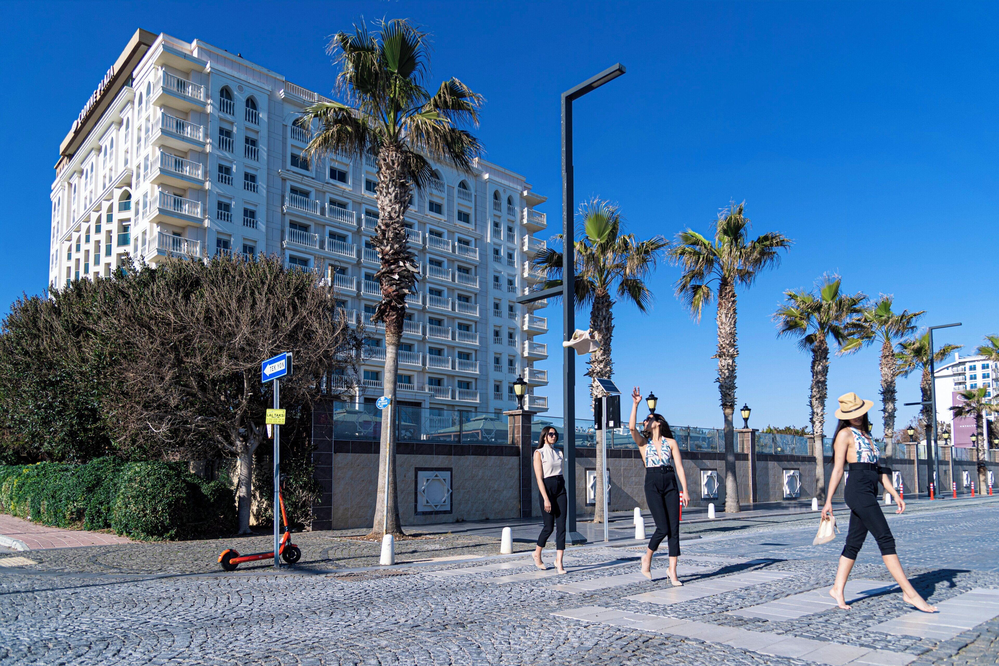 A building with multiple balconies, palm trees, and a cobblestone street.