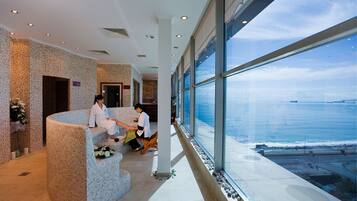 A reception area with a curved seating arrangement, large windows offering a view of the sea, and a tiled floor.