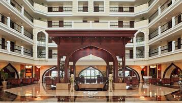 Un vestíbulo de hotel de varios niveles con un espacio central abierto, varios balcones y una imponente arcada de madera.