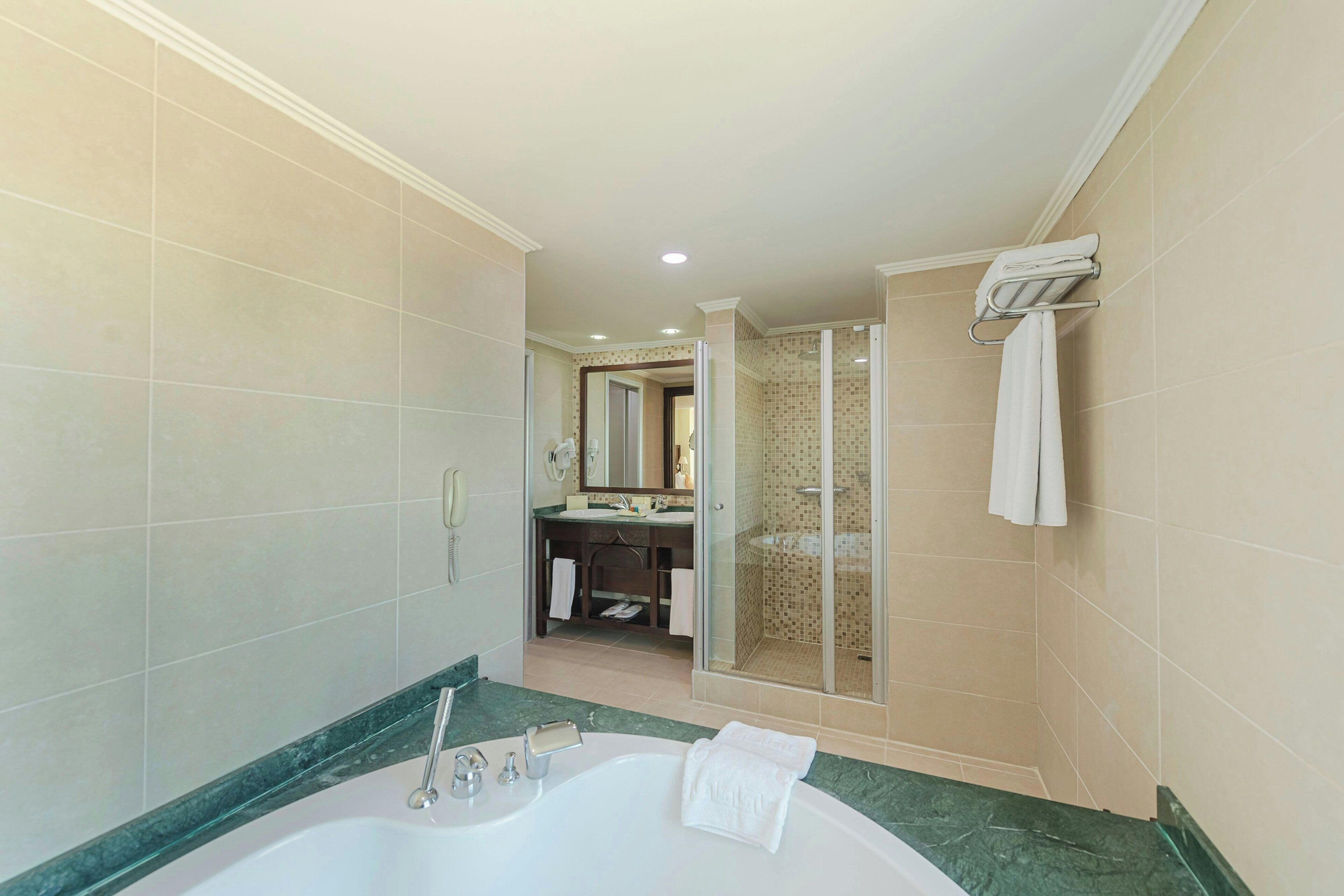 A bathroom with a large bathtub, a shower area, and a vanity with a mirror.