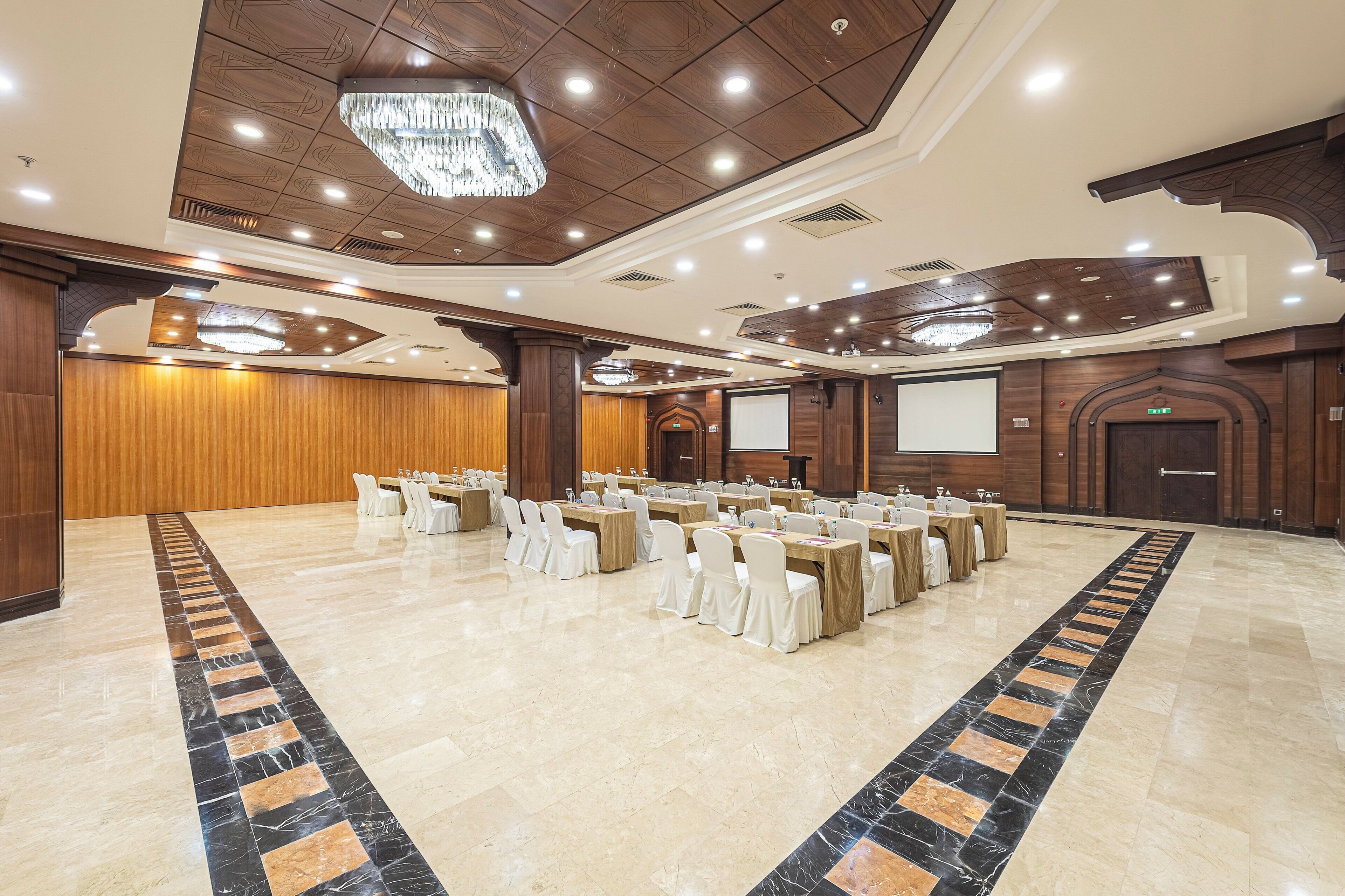 A large conference room with a long table, white chairs, and a projector screen.
