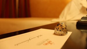 Et hotelværelse med et pænt opdækket bord, et stykke papir med en logo og en indpakket genstand på bordet.
