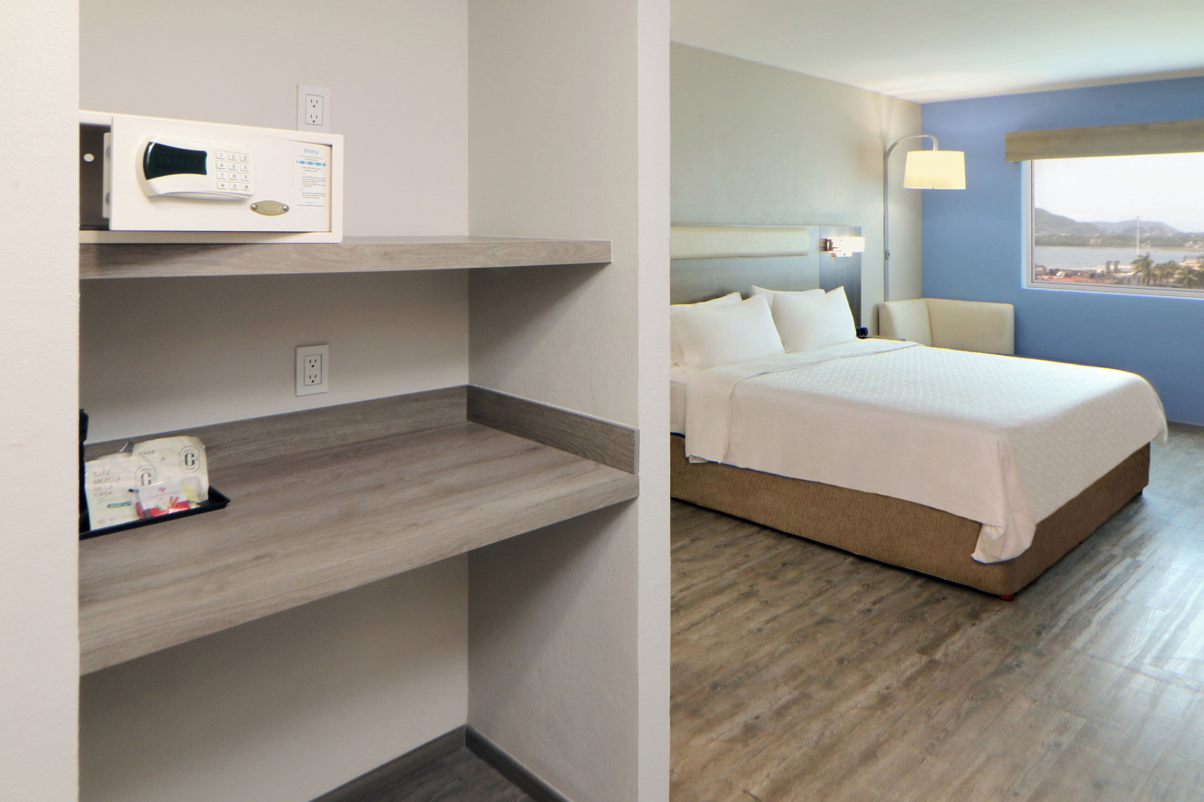 Una habitación de hotel con cama, mesita de noche, microondas y ventana con vistas.