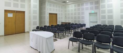 A conference room with rows of chairs, a white table, and soundproofing panels on the walls.