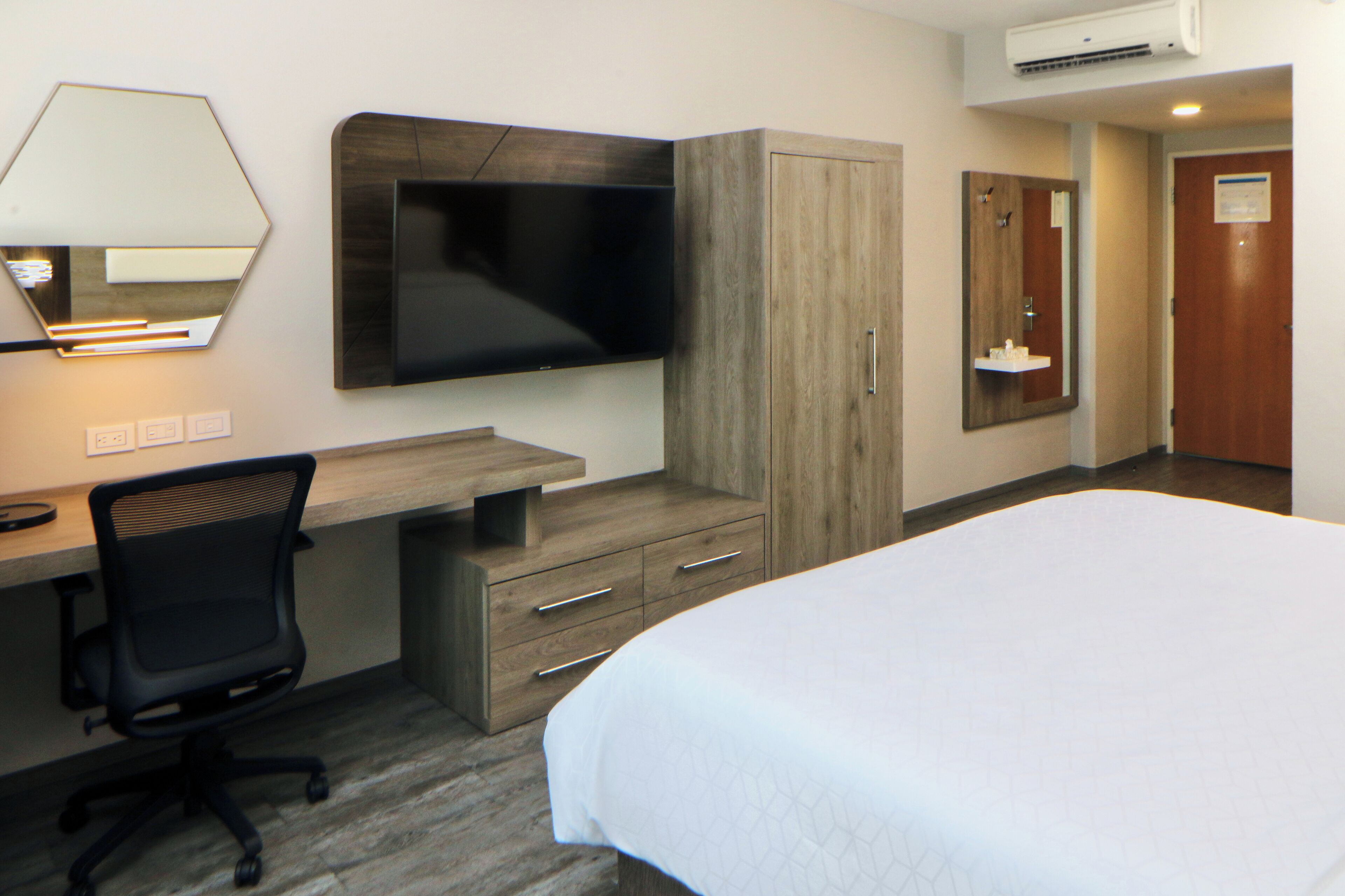 Ein Hotelzimmer mit Bett, Schreibtisch mit Stuhl, Fernseher, Kleiderschrank und Bad.