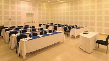 Un salón de conferencias con varias mesas y sillas, equipado con botellas de agua y tarjetas de identificación.