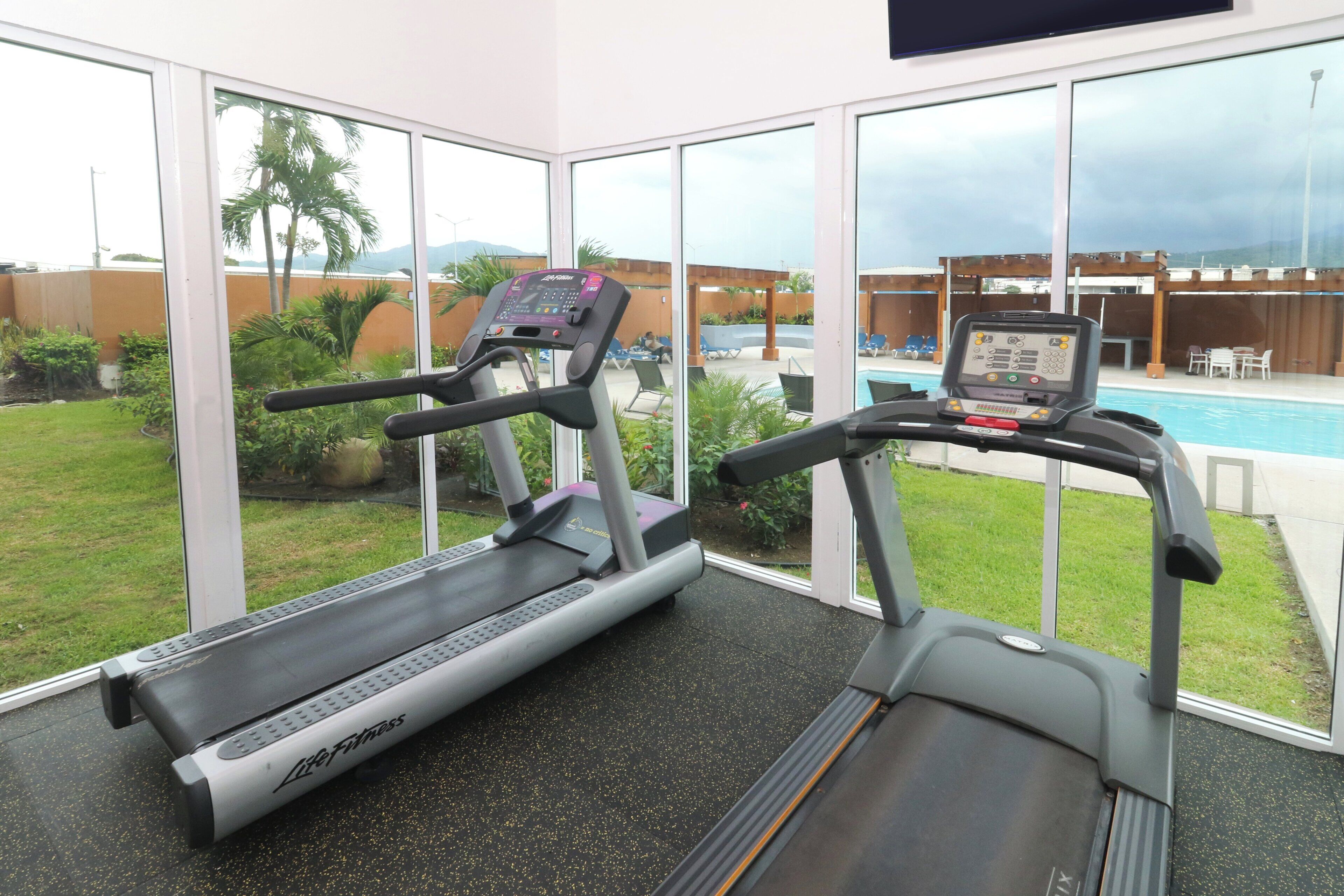 A gym with treadmills and a pool view.