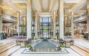 A spacious lobby with a central fountain, multiple seating areas, and a grand staircase.