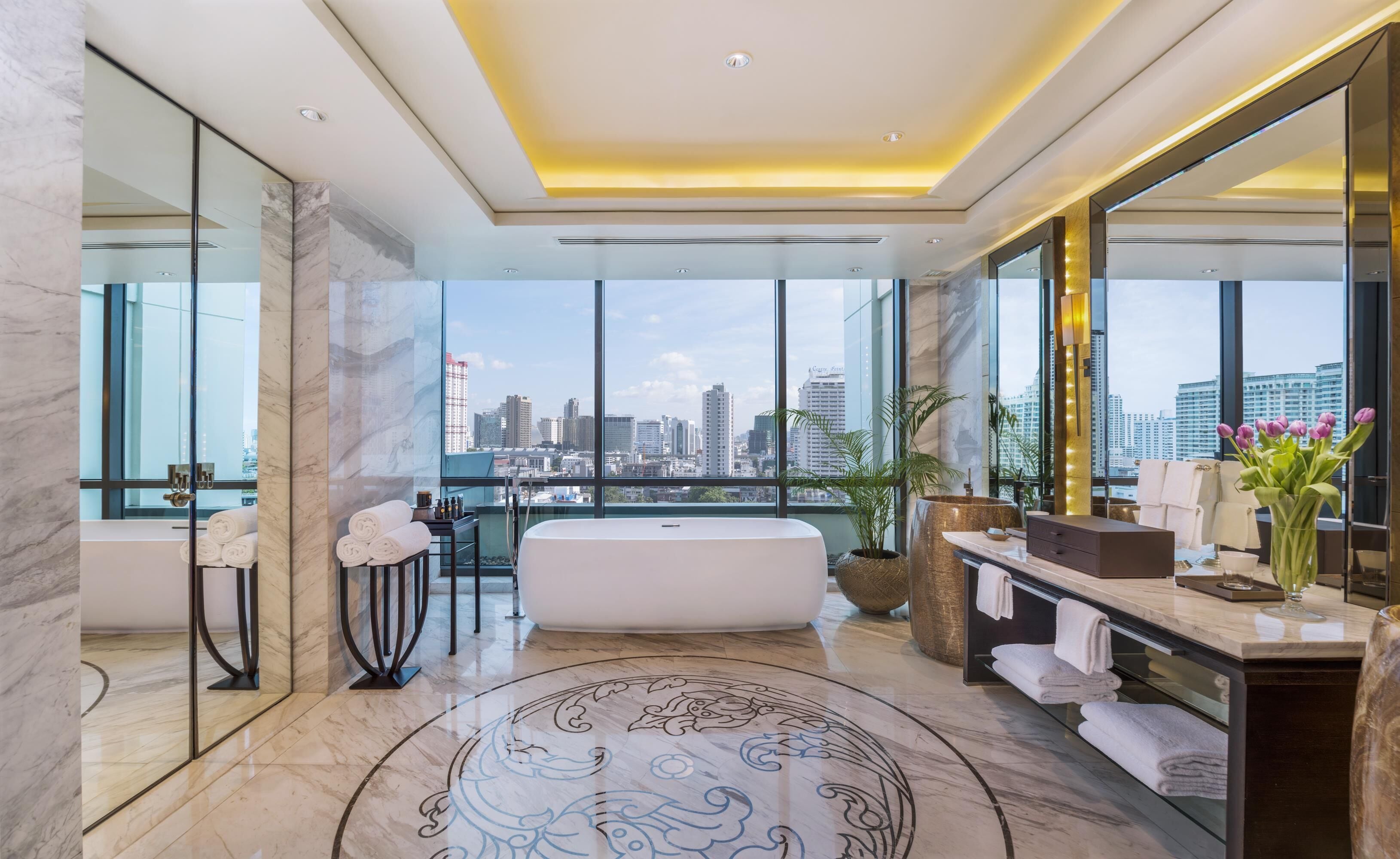 Ein modernes Badezimmer mit einer großen Badewanne, einem Waschtisch mit Spiegel und Blick auf die Stadtlandschaft.