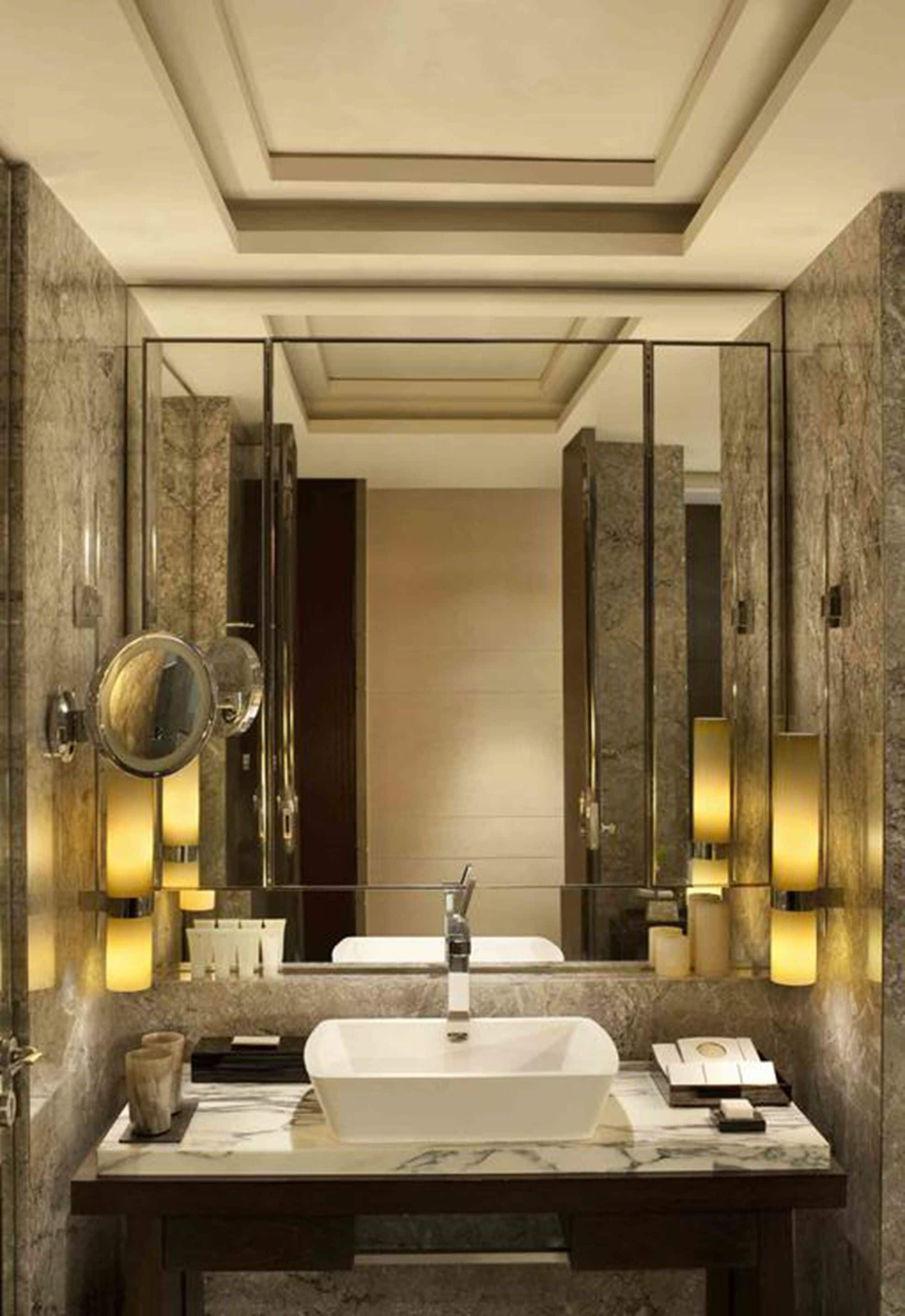 Un baño moderno con un espejo grande, un lavabo sobre encimera e iluminación empotrada.