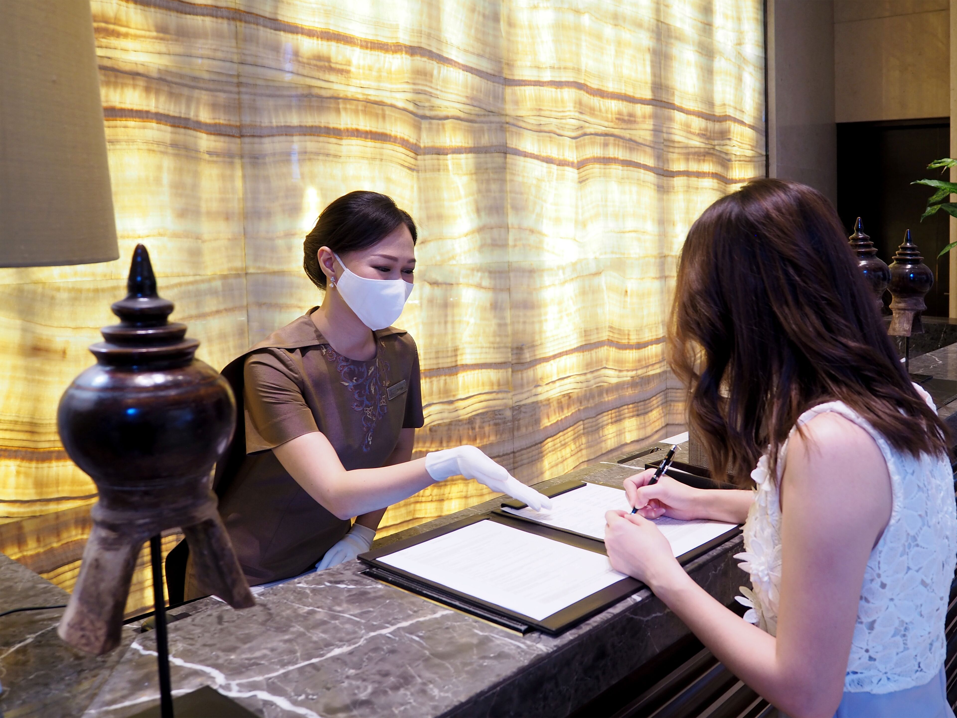 A reception desk with a marble counter, a decorative lamp, and a patterned wall in the background.