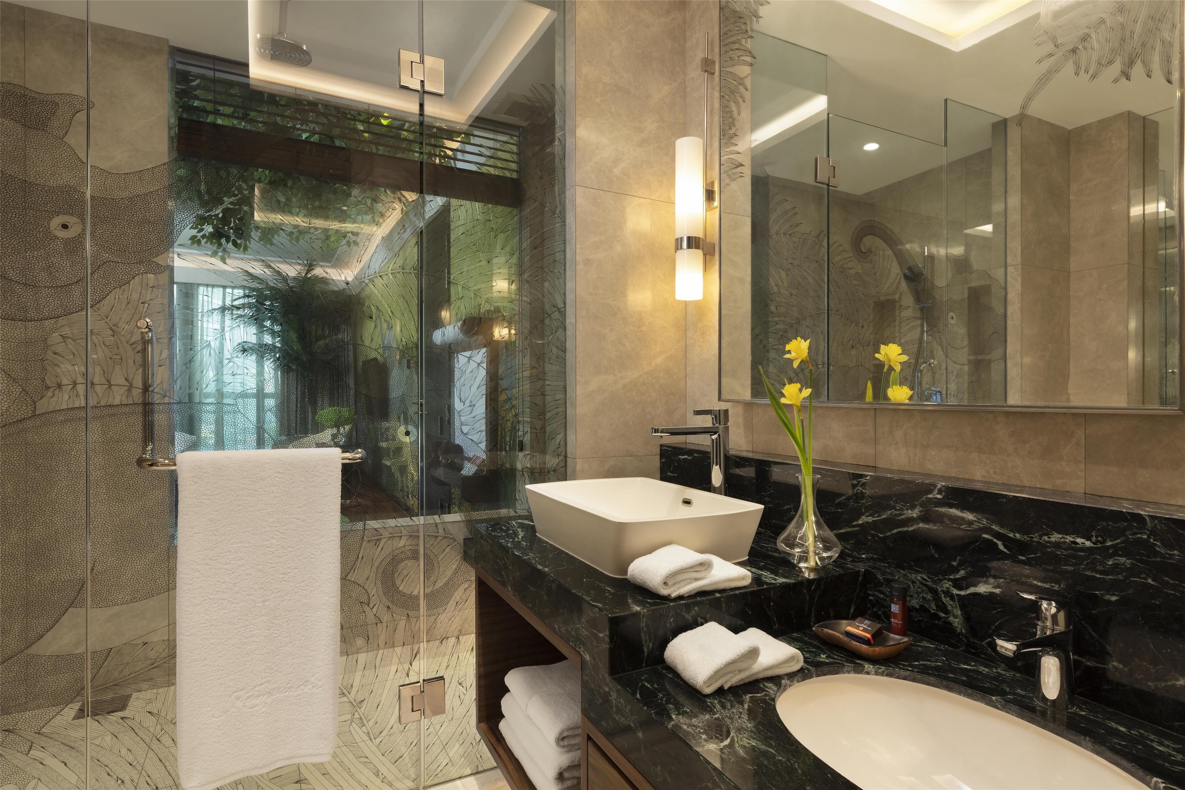 A modern bathroom with a large mirror, a white sink, and a glass-enclosed shower area.
