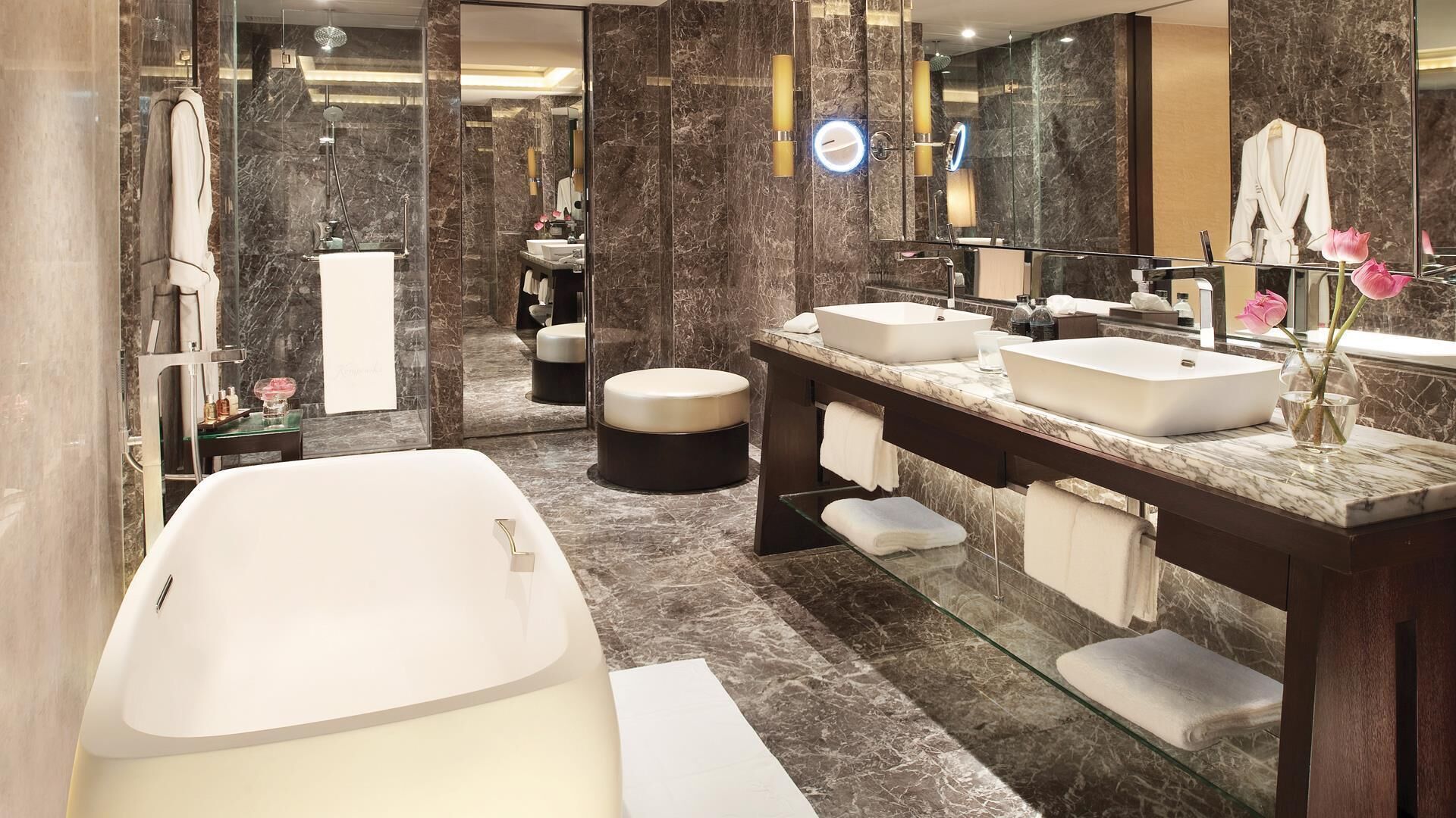 Un baño moderno con una bañera independiente, dos lavamanos, un tocador y un espejo grande.