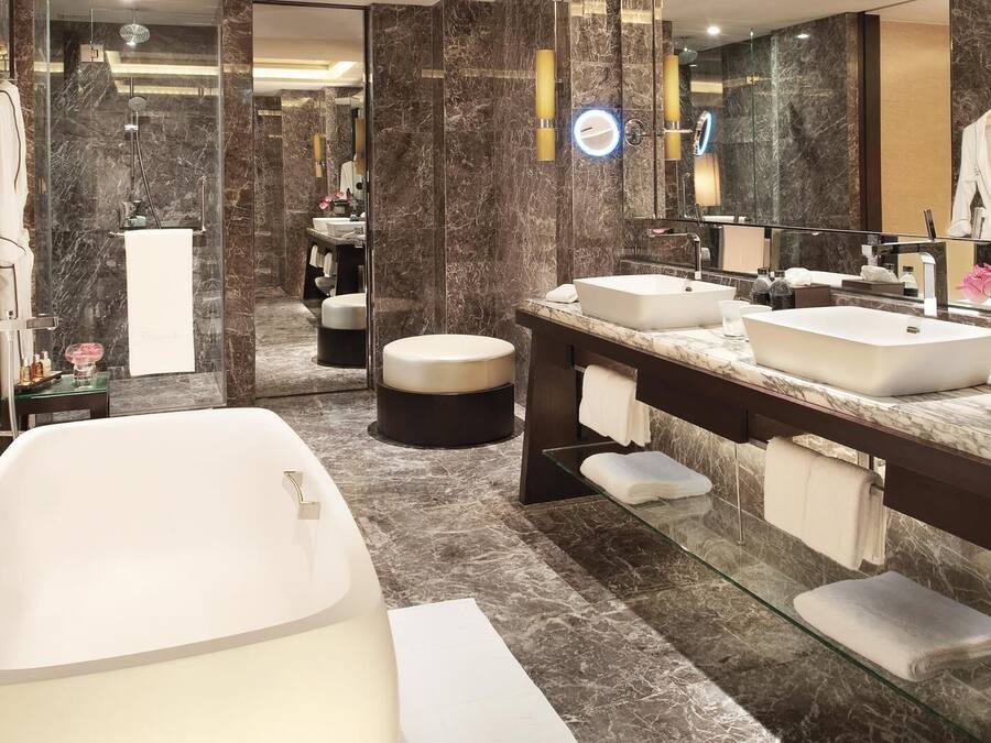 A modern bathroom with a freestanding bathtub, two sinks, a vanity, and a large mirror.