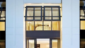 Un hôtel moderne doté d’une piscine, avec un hall d’entrée à deux niveaux, un espace repas comprenant une table et des chaises, et un balcon bien visible.