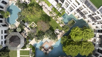 Vista aérea de un hotel con varias piscinas, exuberante vegetación y arquitectura moderna.