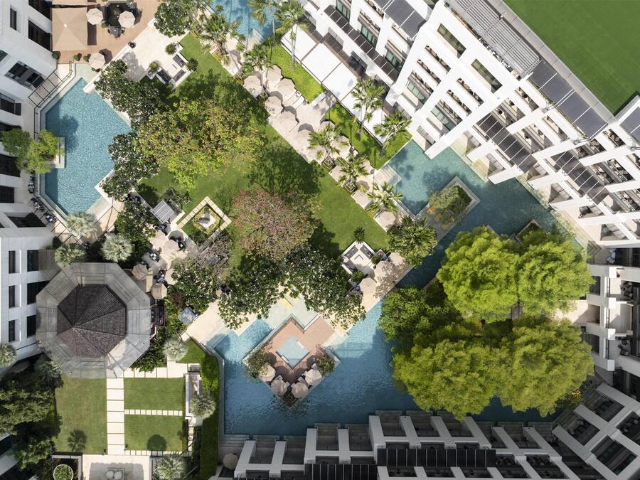 Vista aérea de un hotel con varias piscinas, exuberante vegetación y arquitectura moderna.