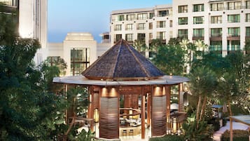 A modern hotel with a rooftop garden and a wooden gazebo.