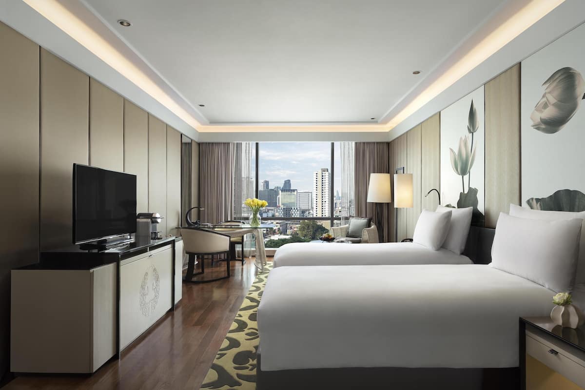 Ein Hotelzimmer mit einem großen Bett, einem Schreibtisch mit Fernseher und Blick auf die Stadt.