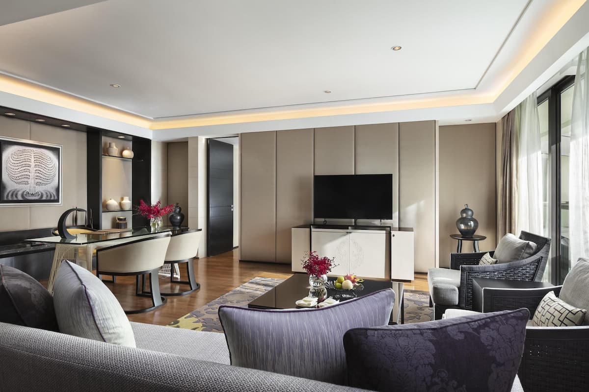 Ein modernes Wohnzimmer mit einer Couch, Sesseln, einem Couchtisch und einem Fernseher.