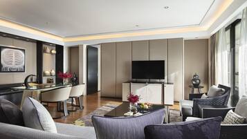 A modern living room with a sofa, armchairs, a coffee table, and a TV.
