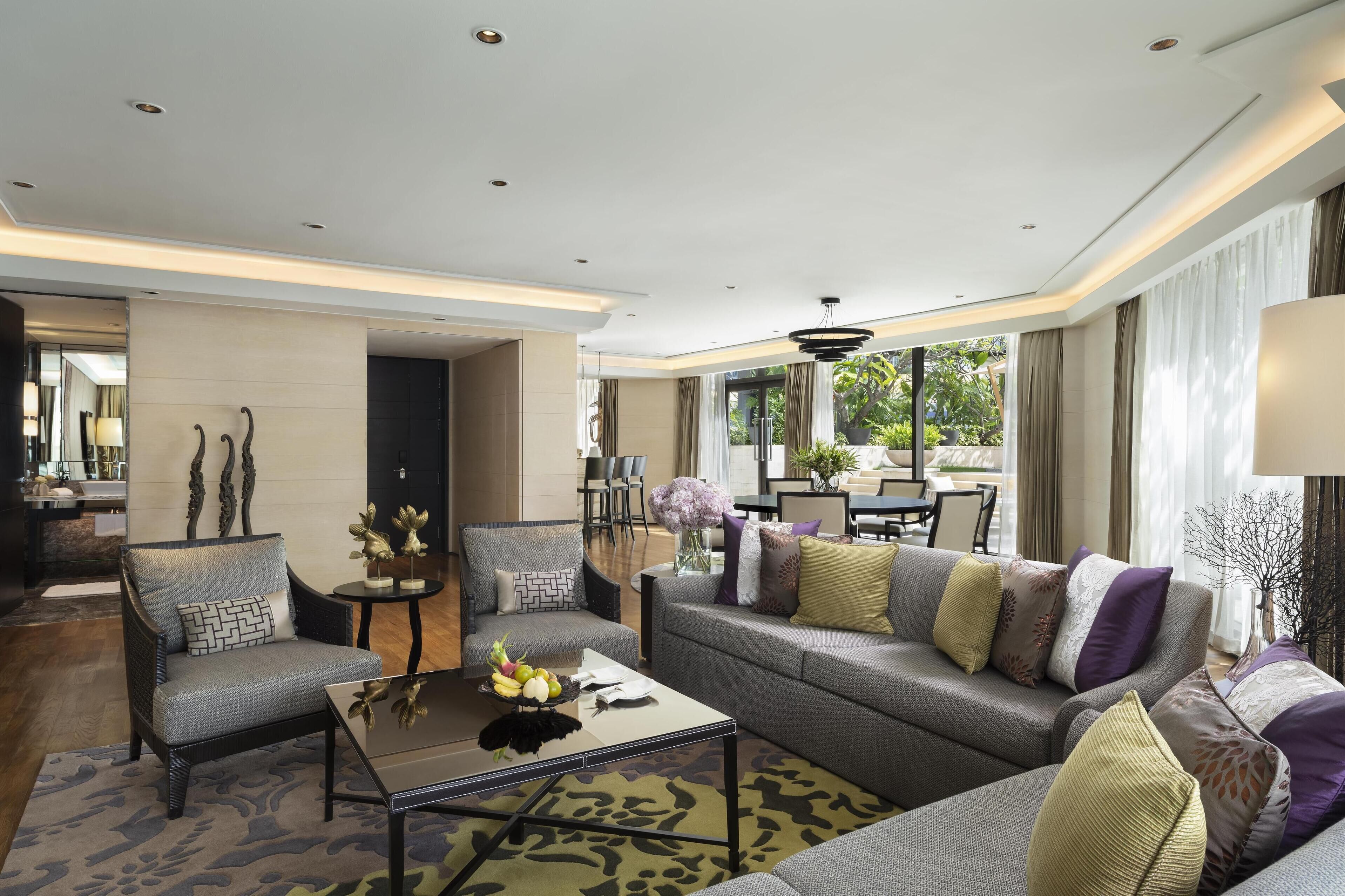 A modern living room with a sofa, armchairs, a coffee table, and a dining area.