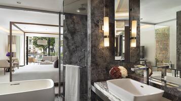 A modern bathroom with a large bathtub, a marble countertop, and a large mirror.