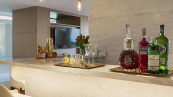 Una cocina moderna con encimera de mármol, televisor y una variedad de botellas y vasos.