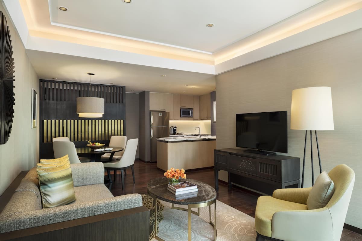 Ein modernes Hotelzimmer mit Wohnbereich, Essplatz und Küchenzeile.