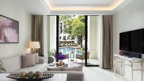 Un salon moderne comprenant un canapé, une table basse agrémentée d’objets décoratifs, un téléviseur et une vue sur un espace piscine extérieur.