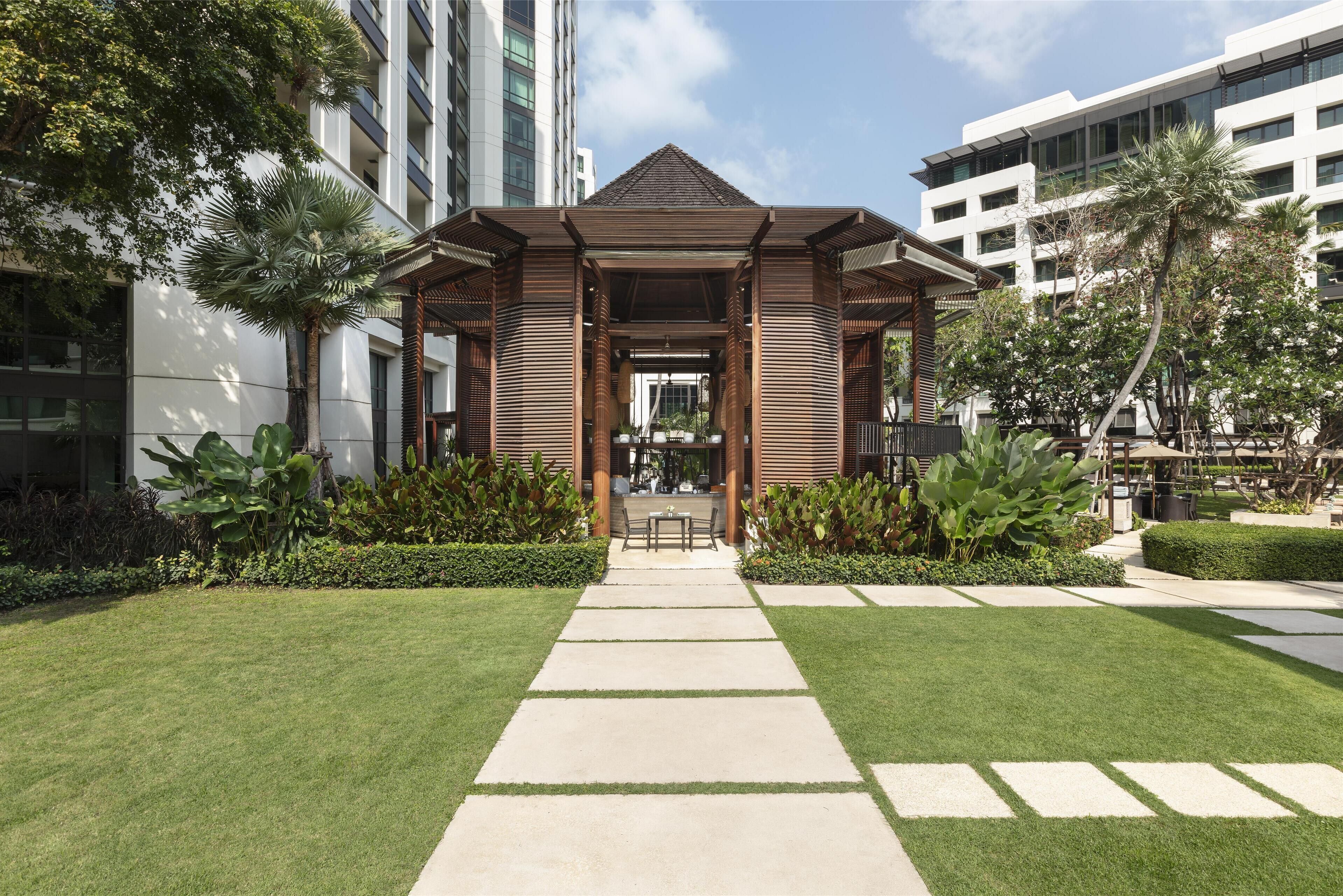 Un edificio moderno con un acceso cubierto, un camino pavimentado y jardines bien cuidados.