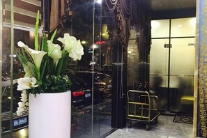A hotel entrance with a potted plant, a glass door, and a metal cart. - Zhanjiang Zhongtailai Hotel (Yifu International Plaza Branch) (Zhanjiang)