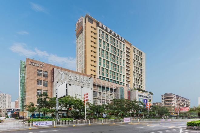 Un hotel de varios pisos con un letrero llamativo, un estacionamiento y un cielo despejado.