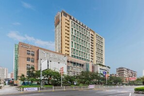 Un hôtel à plusieurs étages, doté d’une enseigne bien visible, d’un parking et surplombant un ciel dégagé.