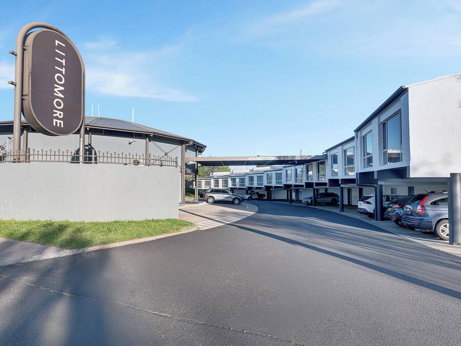 A parking area with a sign reading "LITTMORE" and a row of parked cars.