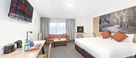 Habitación de hotel con cama, escritorio con computadora, televisor y un cuadro en la pared.