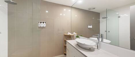 Un baño moderno con un espejo grande, un lavabo redondo y una zona de ducha.