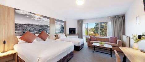 A hotel room with a large bed, a sofa, a desk, and a TV.