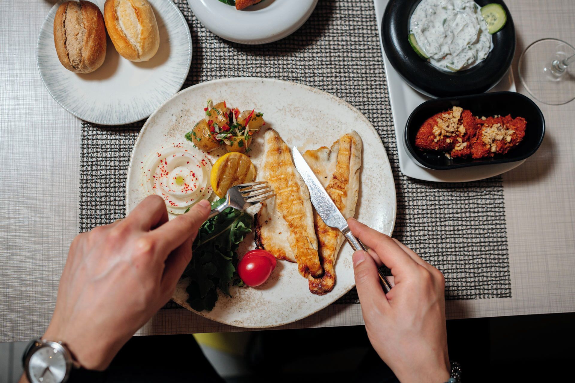 A dining table with a plate of food, a fork, and a knife.