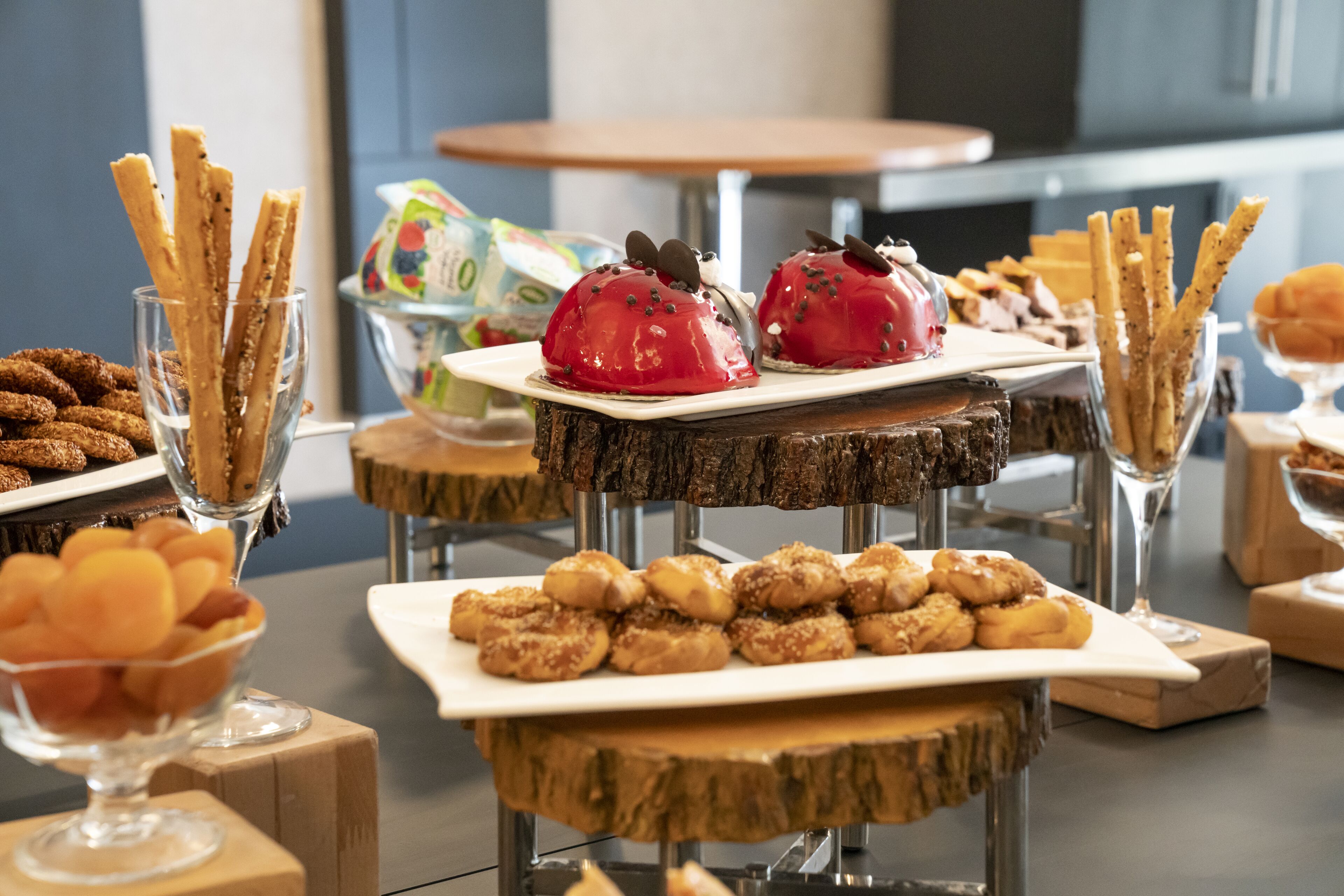 A buffet with various food items including pastries, fruits, and snacks arranged on wooden stands.