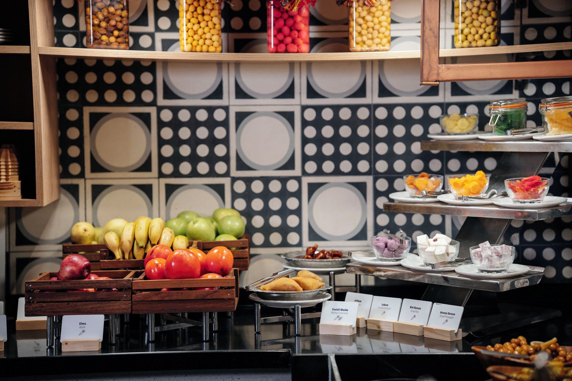 Un bufé con diversas frutas y platos, incluyendo manzanas, plátanos y una selección de quesos.
