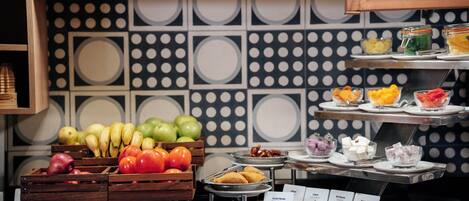 Un bufé con diversas frutas y platos, incluyendo manzanas, plátanos y una selección de quesos.
