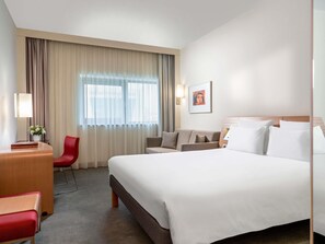 A hotel room with a large bed, a desk, a chair, a sofa, and a window with curtains. - Novotel Gaziantep (Gaziantep)