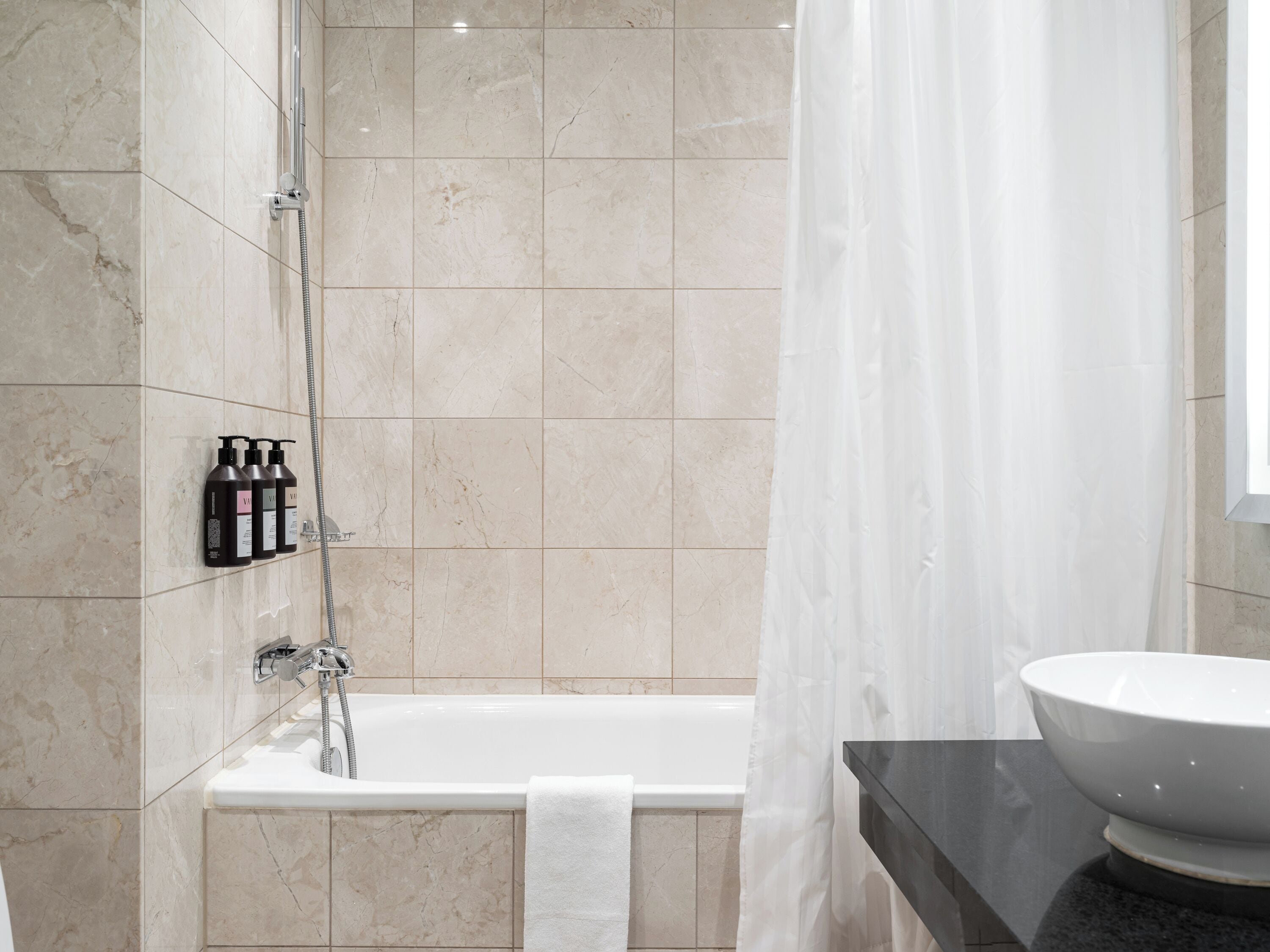 A modern bathroom with a bathtub, a shower, and a vanity with a large sink.