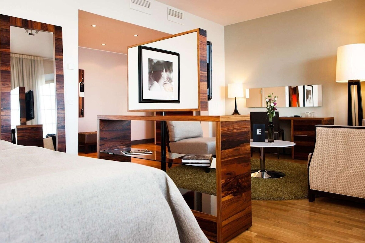 Una habitación de hotel con cama, escritorio, silla, mesita y sofá.