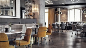 Un interior de restaurante moderno con mesas redondas, sillas de terciopelo y lámparas colgantes.