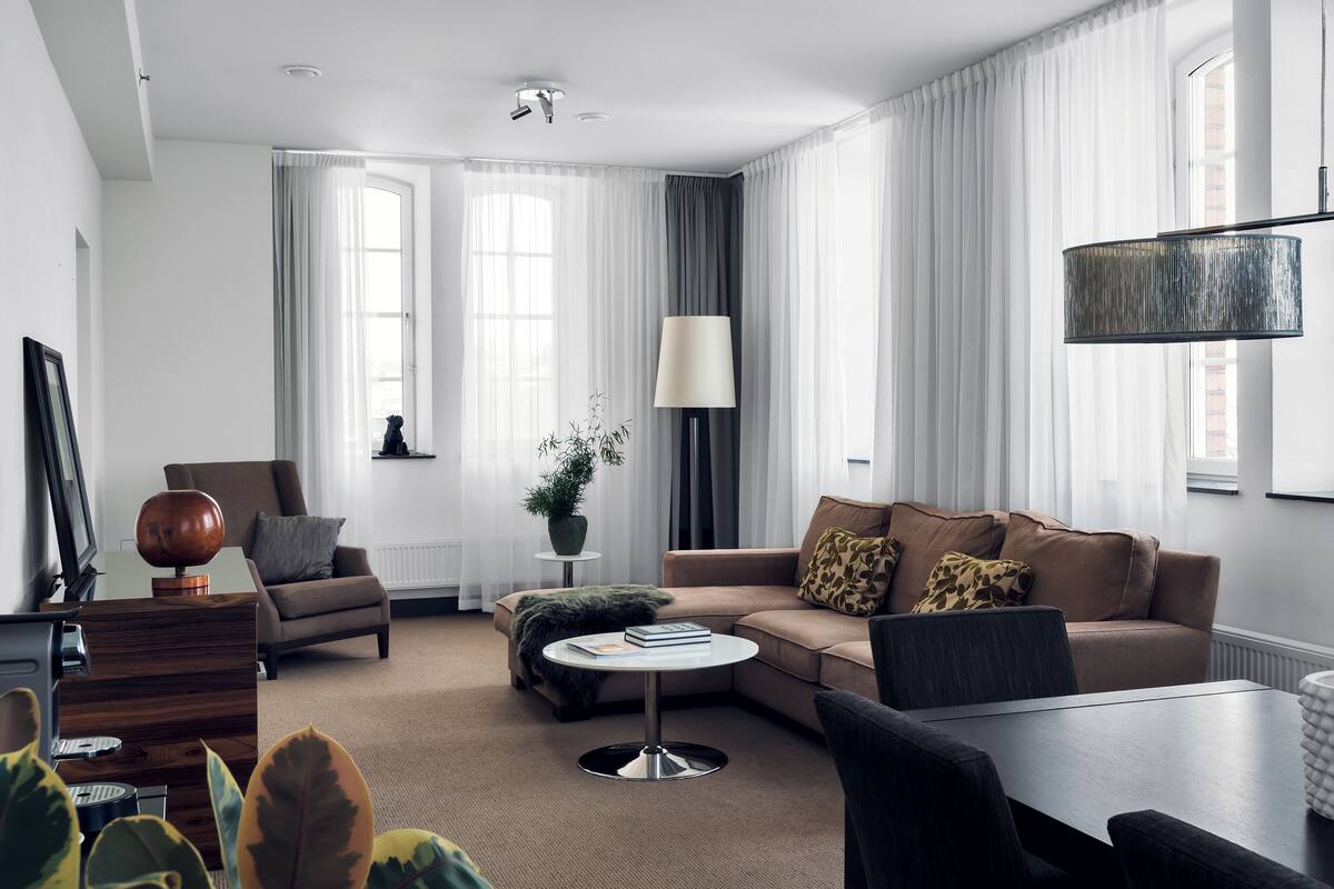 Una sala de estar moderna con sofá, sillón, mesa de centro y mesa de comedor.
